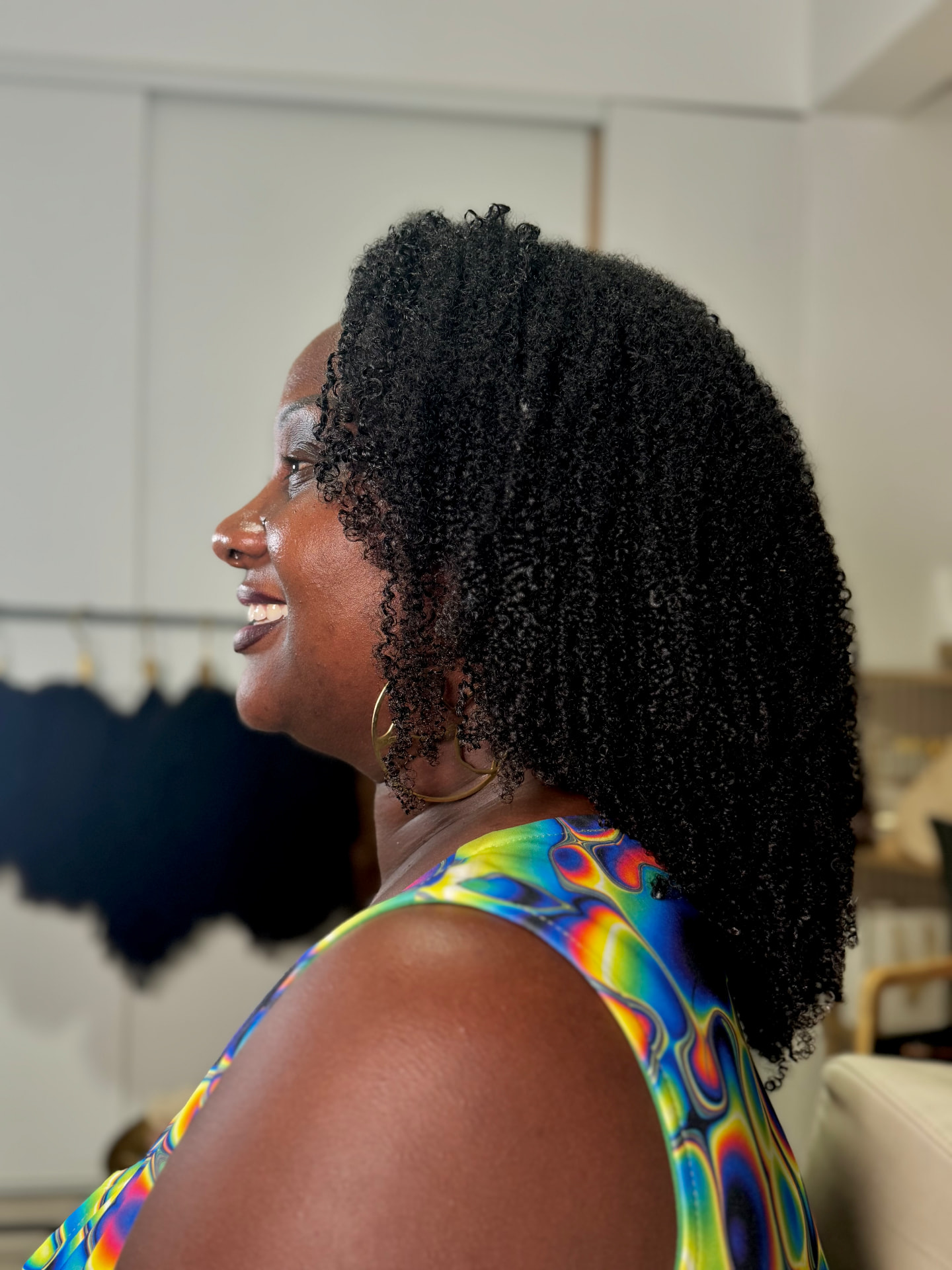 Cliente TBW de profil, sourire et demi-perruque texturée volumineuse