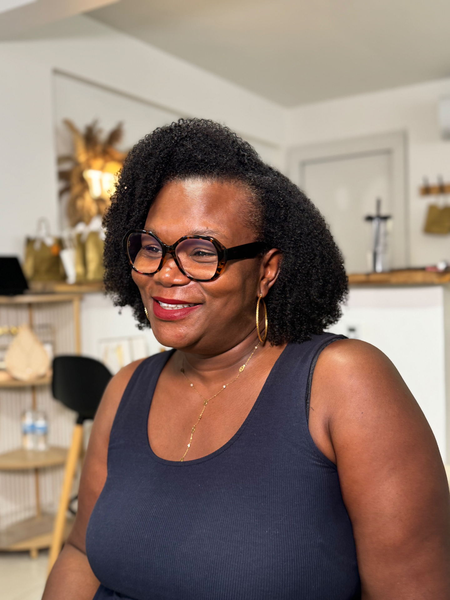 Cliente TBW souriante au showroom, cheveux texturés volumineux